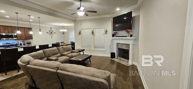 living room with ceiling fan with notable chandelier, crown molding, a high end fireplace, and dark hardwood / wood-style floors