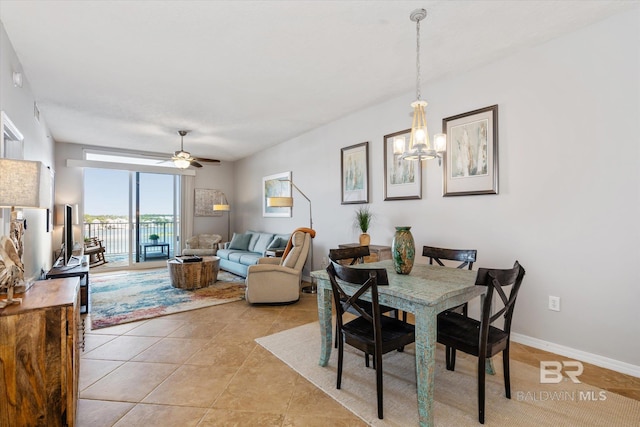 dining space with ceiling fan with notable chandelier, baseboards, and light tile patterned floors