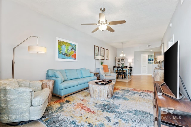 living room with ceiling fan, a textured ceiling, wood finished floors, and visible vents