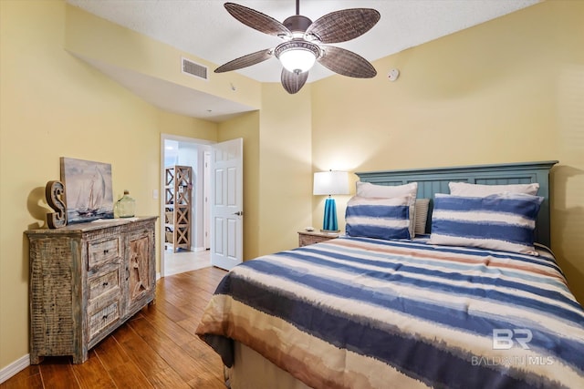 bedroom featuring a ceiling fan, wood finished floors, visible vents, and baseboards