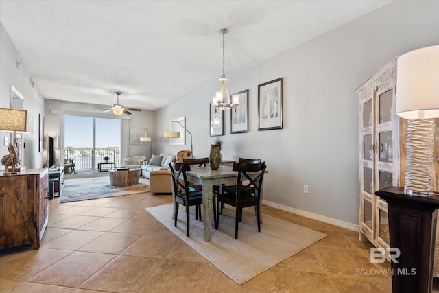 dining room with ceiling fan with notable chandelier, light tile patterned flooring, and baseboards