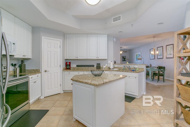 kitchen featuring visible vents, white cabinets, a kitchen island, light tile patterned flooring, and a peninsula