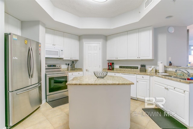 kitchen with stainless steel appliances, a sink, visible vents, a center island, and a tray ceiling