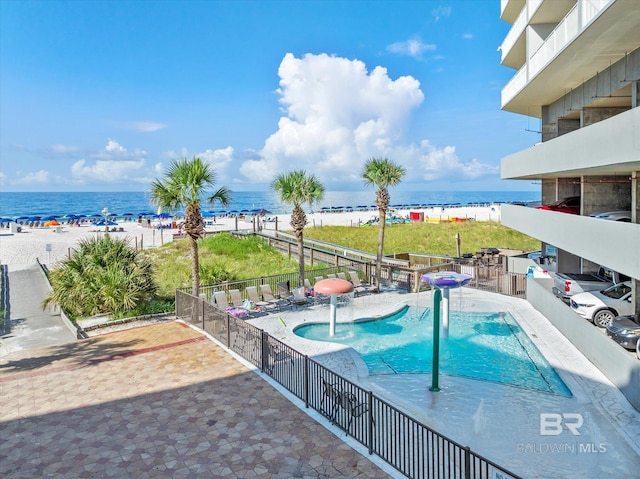 view of pool with a water view, pool water feature, a view of the beach, and a patio area