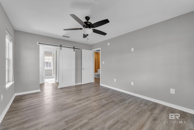 24477 Harvester Dr, Loxley, AL 36551 - unfurnished bedroom with a barn door, baseboards, and wood finished floors