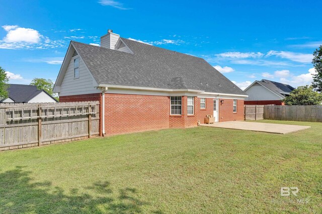 24477 Harvester Dr, Loxley, AL 36551 - rear view of property featuring brick siding, a fenced backyard, a chimney, a lawn, and a patio