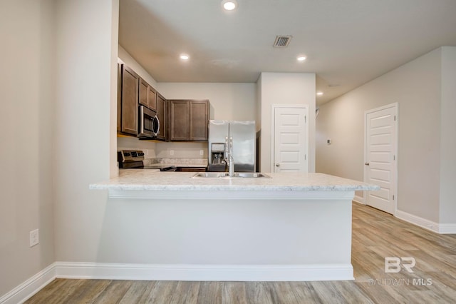 kitchen featuring dark brown cabinetry, sink, kitchen peninsula, light hardwood / wood-style floors, and appliances with stainless steel finishes