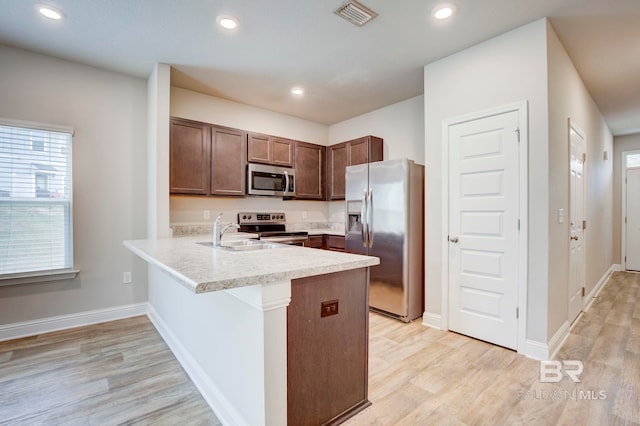 kitchen featuring kitchen peninsula, sink, appliances with stainless steel finishes, and light hardwood / wood-style flooring