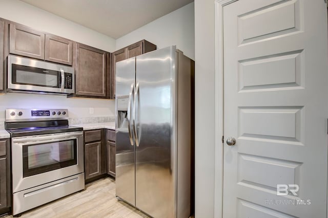 kitchen featuring appliances with stainless steel finishes, light hardwood / wood-style floors, and dark brown cabinets