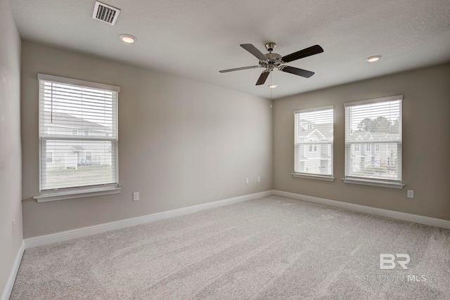 spare room featuring a wealth of natural light, ceiling fan, and light carpet