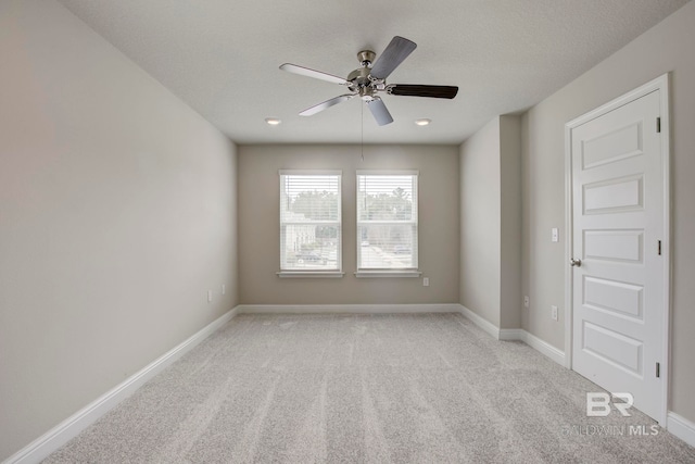 empty room with ceiling fan, light colored carpet, and a textured ceiling