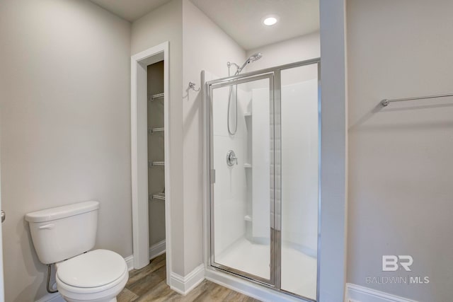 bathroom with hardwood / wood-style flooring, toilet, and walk in shower