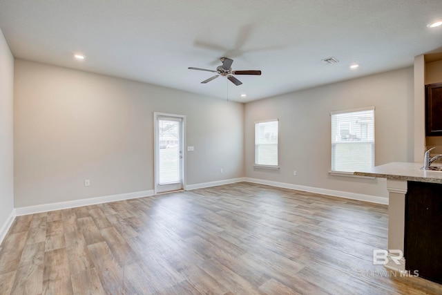 unfurnished living room with ceiling fan, sink, and light hardwood / wood-style flooring