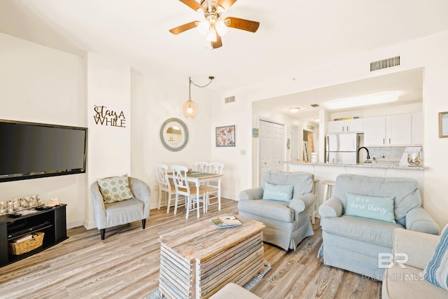 living area featuring visible vents, ceiling fan, and light wood-style flooring