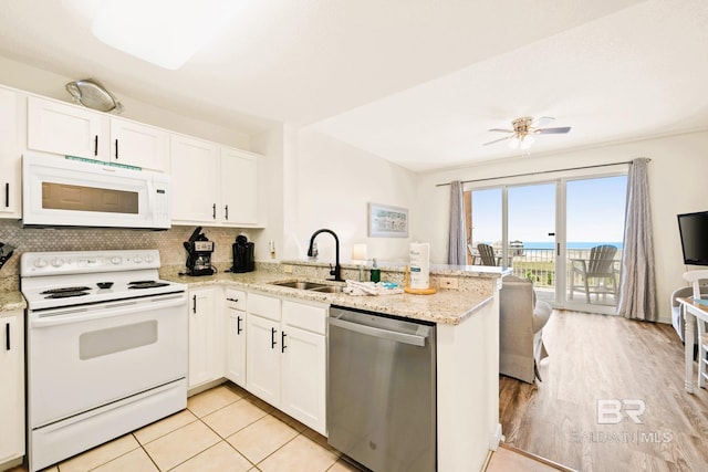 kitchen featuring white appliances, a peninsula, a sink, white cabinetry, and backsplash