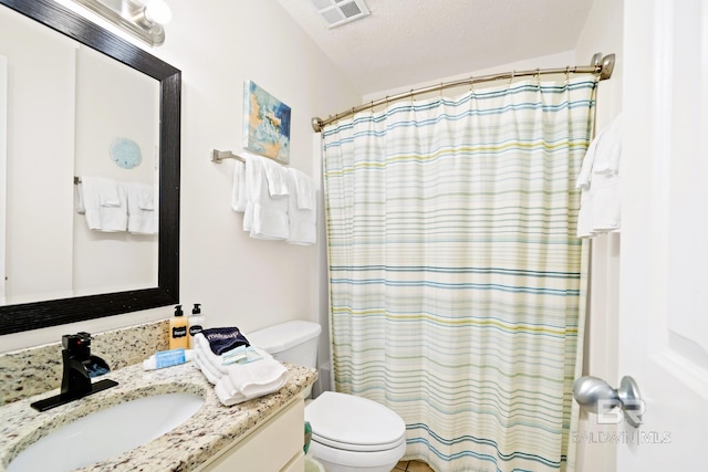 full bathroom featuring curtained shower, visible vents, toilet, vanity, and a textured ceiling