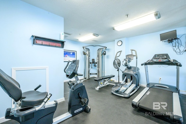 exercise room with a textured ceiling and baseboards