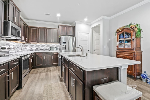 kitchen with a kitchen breakfast bar, a kitchen island with sink, sink, and appliances with stainless steel finishes