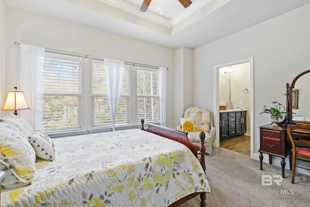 carpeted bedroom with ceiling fan, a raised ceiling, connected bathroom, and multiple windows