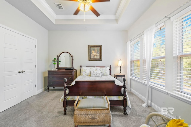 bedroom featuring light colored carpet, a raised ceiling, ceiling fan, and crown molding