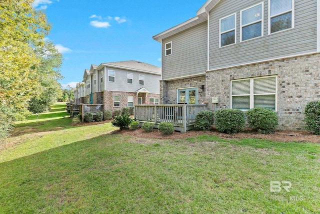 rear view of house featuring a lawn and a wooden deck