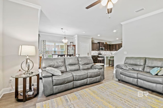 living room with ceiling fan, light wood-type flooring, and crown molding