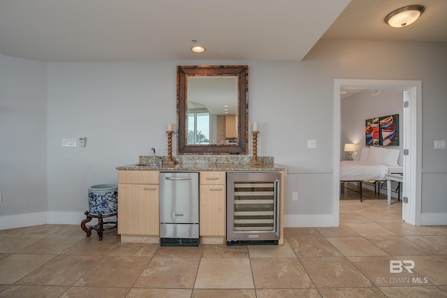 kitchen with stone counters, light brown cabinetry, light tile patterned flooring, and wine cooler