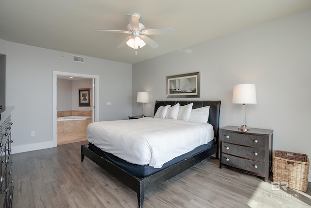 bedroom with light wood-type flooring, ceiling fan, and ensuite bathroom