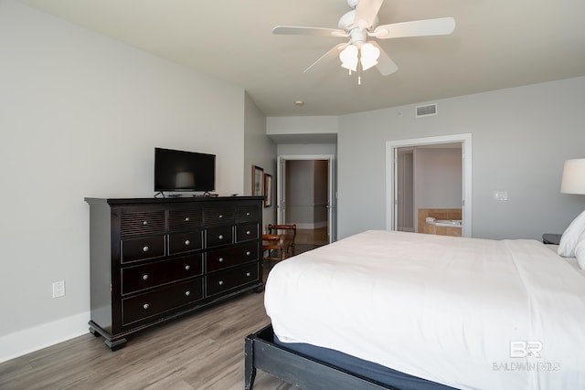 bedroom with light hardwood / wood-style flooring, ceiling fan, and ensuite bath