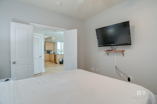 bedroom with light tile patterned floors, ceiling fan, and ensuite bathroom