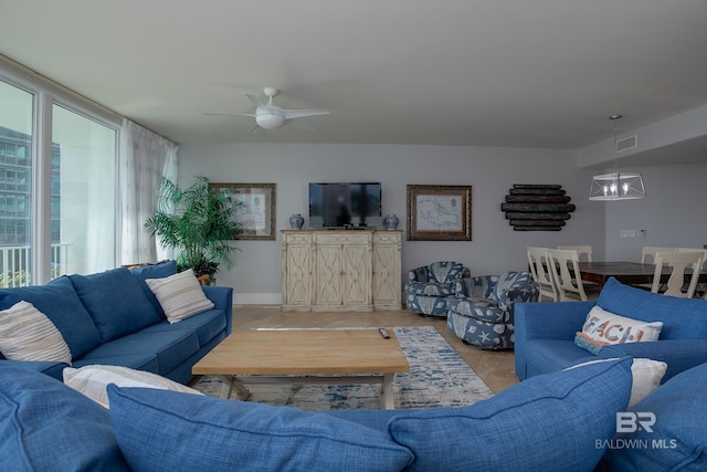 living room featuring a wealth of natural light, ceiling fan with notable chandelier, and light tile patterned floors