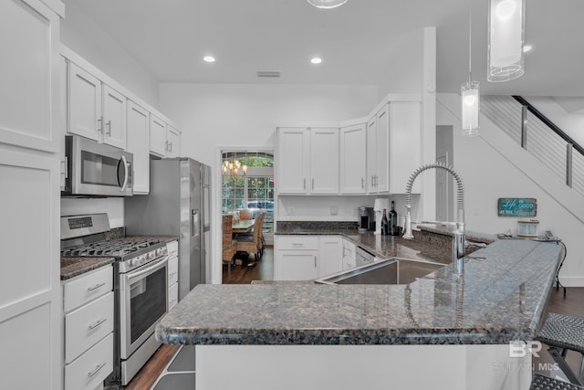 1352 W Fairway Dr, Gulf Shores, AL 36542 - kitchen with appliances with stainless steel finishes, dark wood finished floors, a peninsula, dark stone counters, and white cabinetry