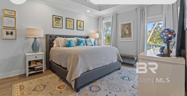 bedroom featuring ornamental molding, multiple windows, baseboards, and wood finished floors