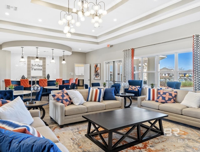 living room with visible vents, french doors, crown molding, a raised ceiling, and a chandelier