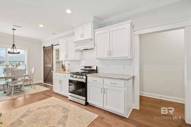 kitchen with visible vents, stainless steel gas range, ornamental molding, a barn door, and tasteful backsplash