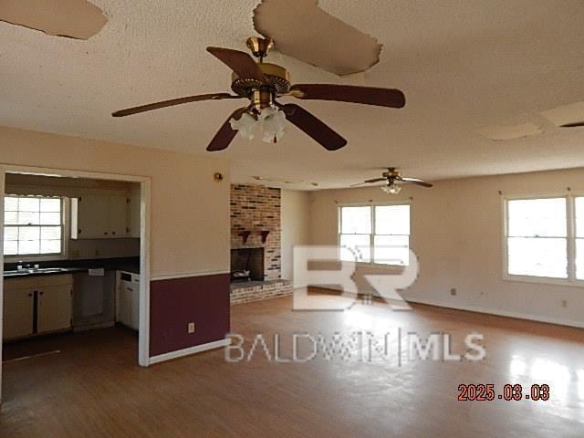 unfurnished living room featuring a fireplace, plenty of natural light, and wood finished floors