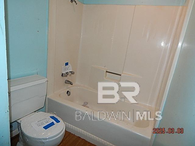 full bath featuring bathtub / shower combination, wood finished floors, and toilet