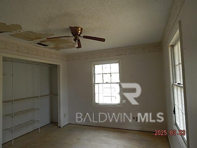 unfurnished bedroom featuring ceiling fan, a textured ceiling, and a closet