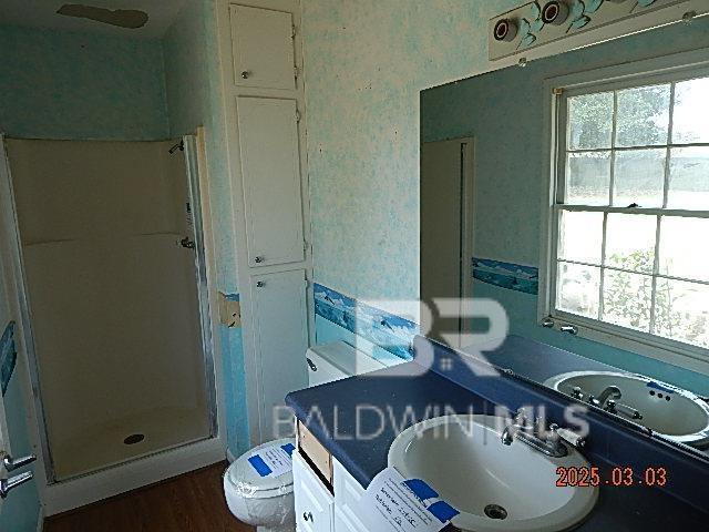 bathroom featuring wallpapered walls, a stall shower, and a healthy amount of sunlight