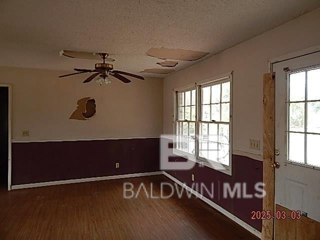 unfurnished room featuring baseboards, a textured ceiling, a ceiling fan, and wood finished floors