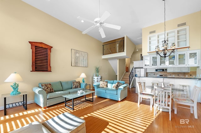 living room with ceiling fan with notable chandelier and light hardwood / wood-style flooring