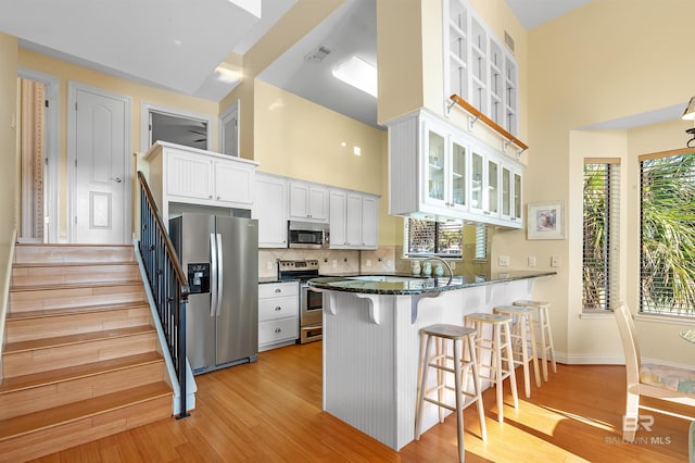 kitchen with kitchen peninsula, white cabinetry, plenty of natural light, and stainless steel appliances