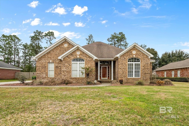 ranch-style house with brick siding, roof with shingles, a front yard, and fence