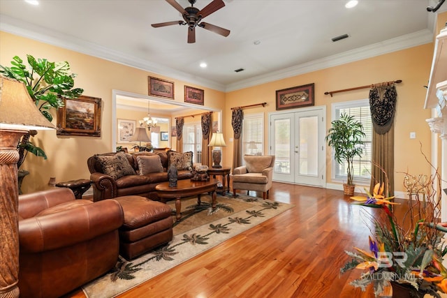 living area featuring french doors, ceiling fan with notable chandelier, wood finished floors, and ornamental molding