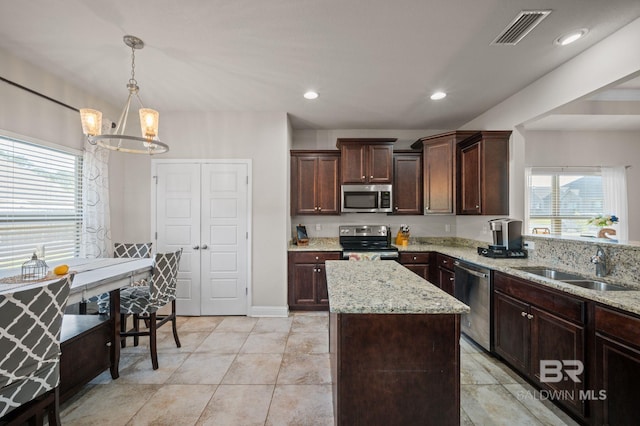 kitchen featuring light stone counters, a chandelier, a center island, stainless steel appliances, and visible vents