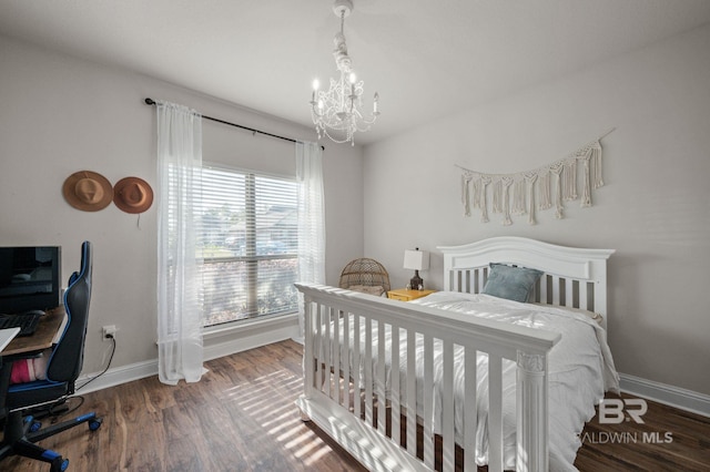 bedroom with baseboards, wood finished floors, and a chandelier