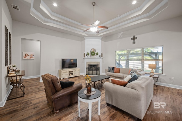 living area with visible vents, ornamental molding, wood finished floors, and a tray ceiling