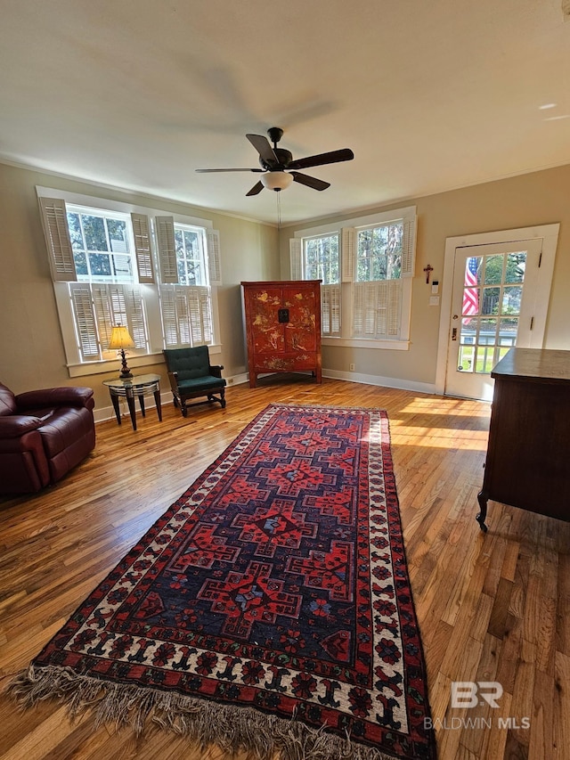 sitting room featuring ceiling fan, wood finished floors, and baseboards