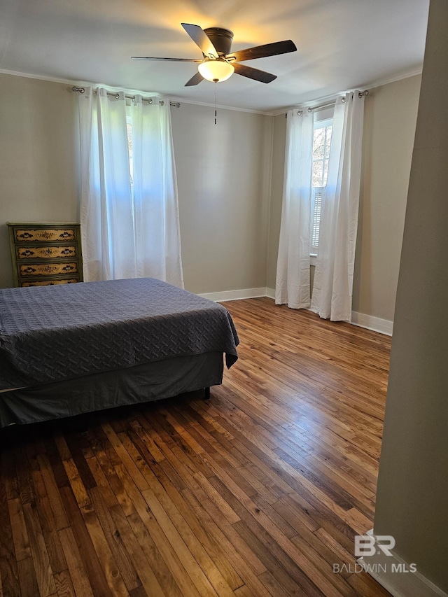 bedroom with a ceiling fan, crown molding, baseboards, and wood finished floors