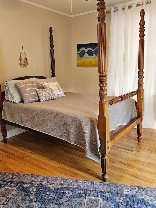 bedroom with crown molding and wood finished floors